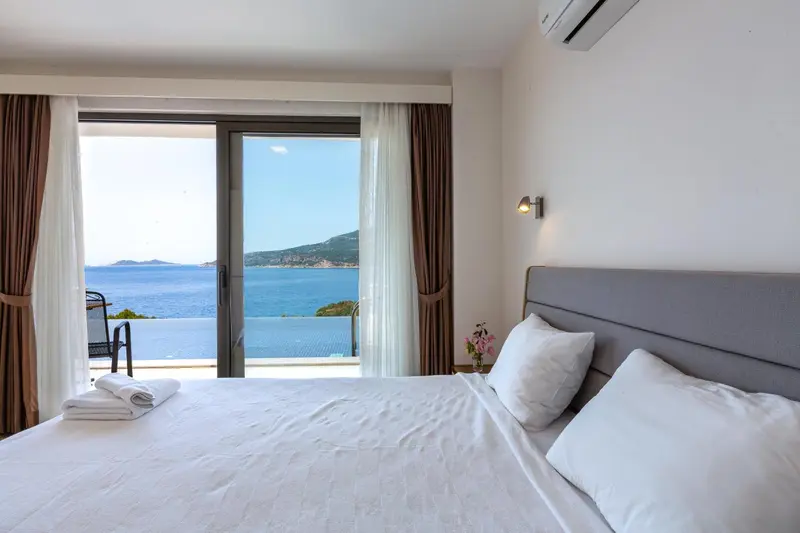 Une chambre lumineuse avec un grand lit donnant sur une vue mer.
