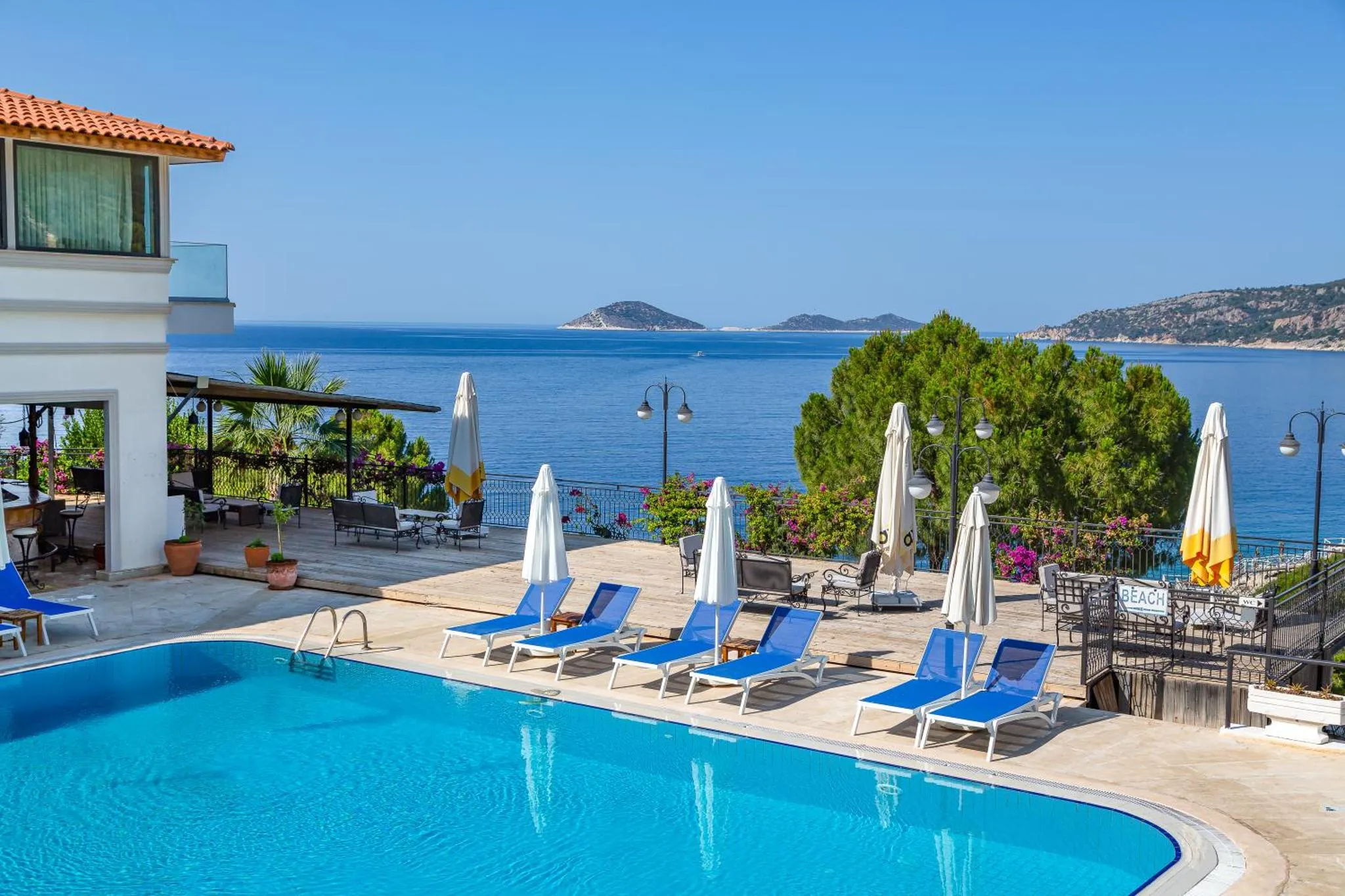 Transats bleus alignés au bord d'une piscine turquoise avec vue sur la mer.
