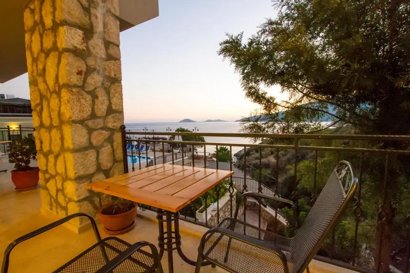 Terrasse avec table et chaises donnant sur la mer au coucher du soleil.