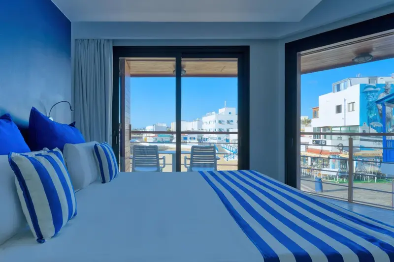 Une chambre lumineuse avec un grand lit donnant sur une vue extérieure.