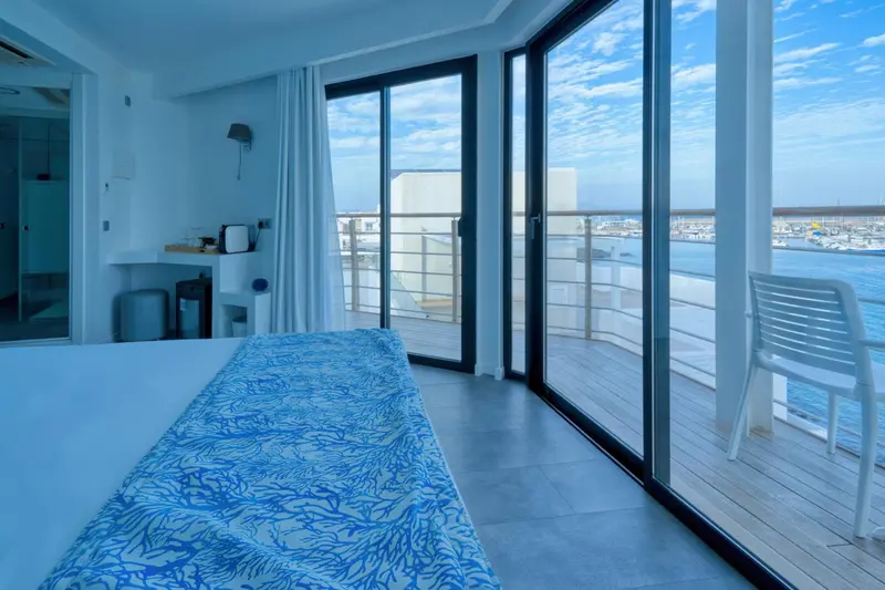 Une chambre lumineuse s'ouvre sur une terrasse avec vue sur la mer.