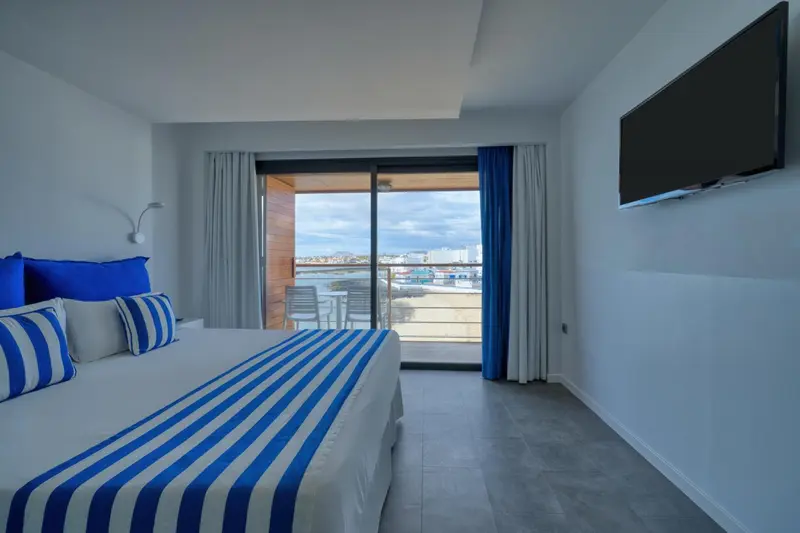 Chambre lumineuse avec un grand lit et une vue sur la mer.