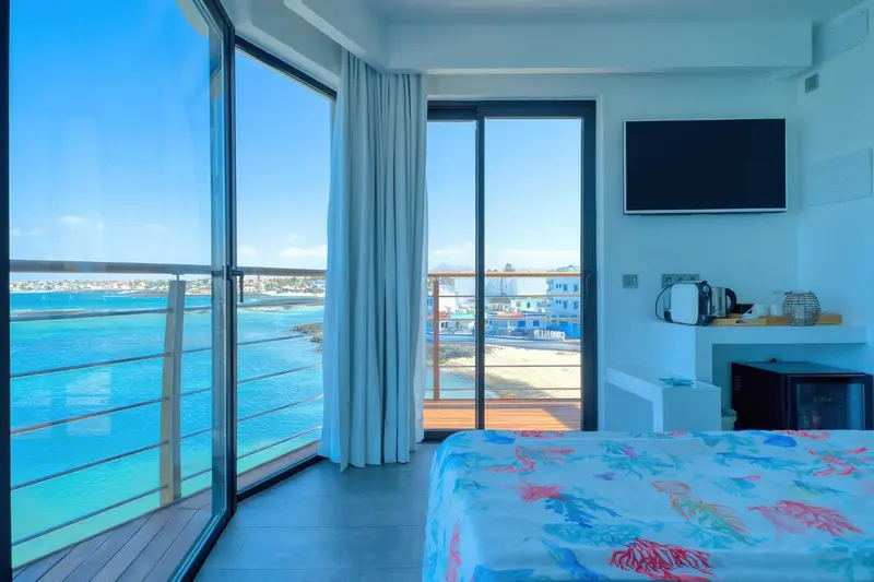 Une chambre lumineuse avec vue sur la mer et un balcon.