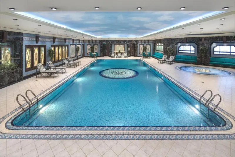 Une piscine intérieure lumineuse avec des chaises longues et une décoration soignée.