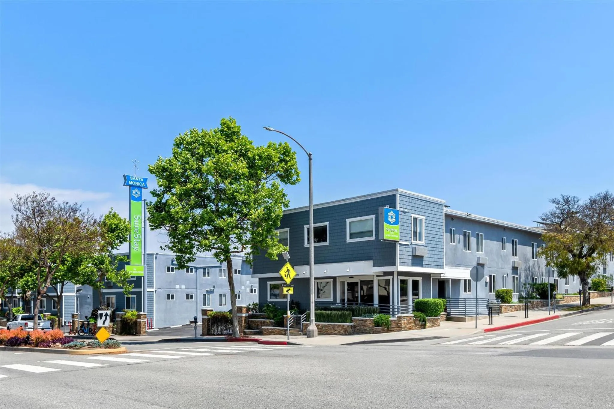 Bâtiment moderne à deux étages avec des arbres et une rue au premier plan.