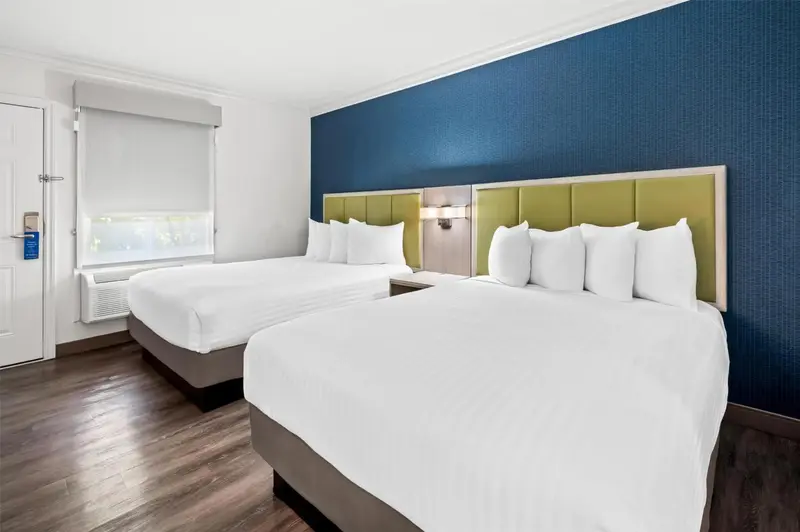 Une chambre d'hôtel avec deux lits doubles et un mur bleu.