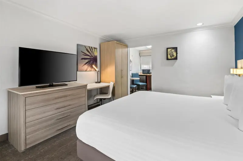Une chambre d'hôtel lumineuse avec un lit blanc et un bureau.