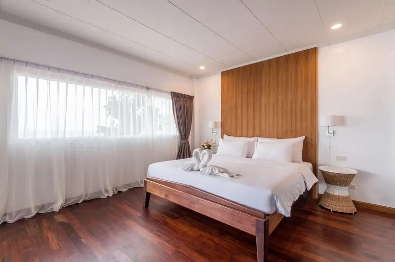 Une chambre lumineuse avec un grand lit et des rideaux blancs.