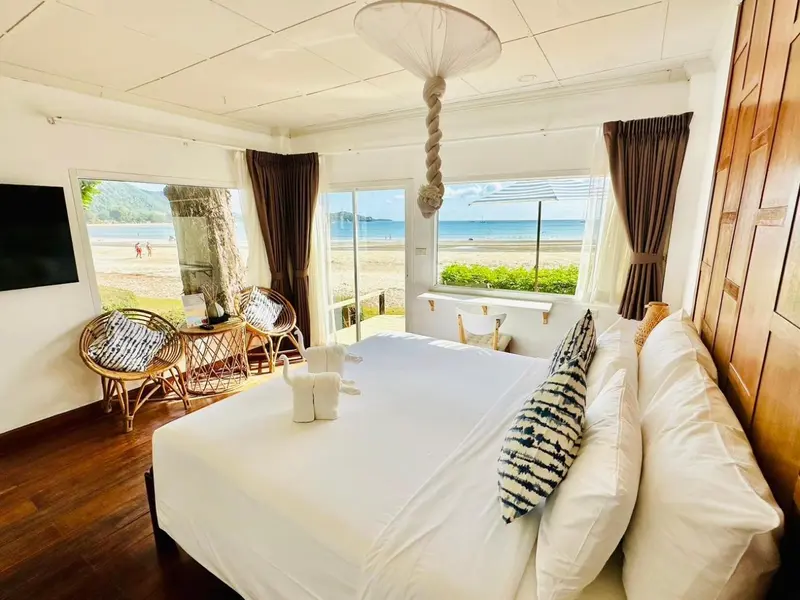 Une chambre lumineuse avec un lit fait et vue sur la plage.