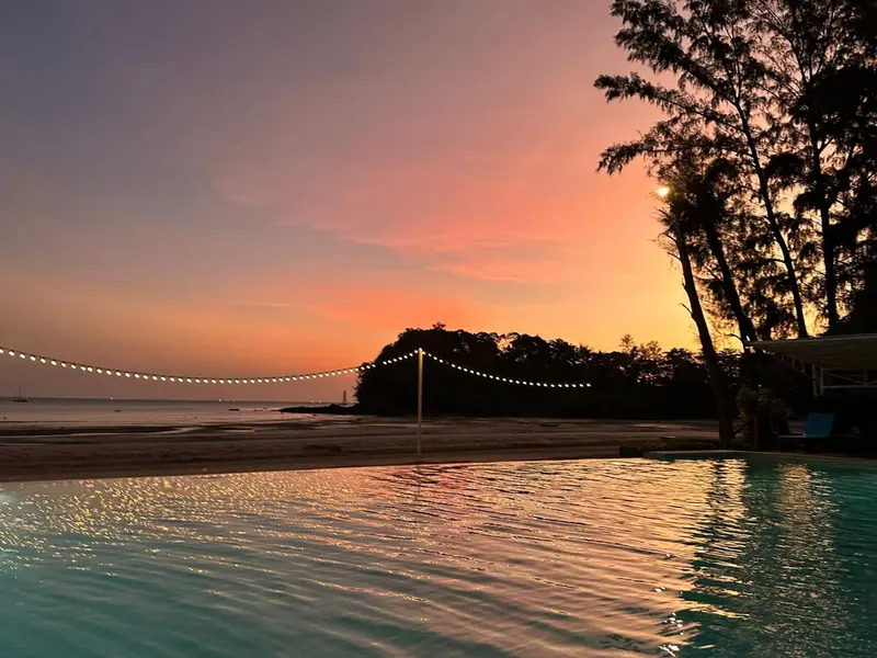 Une piscine reflète les couleurs d'un coucher de soleil sur la mer.