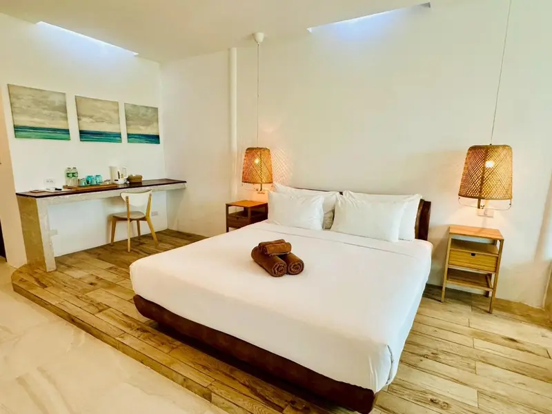 Une chambre lumineuse avec un grand lit et un bureau.