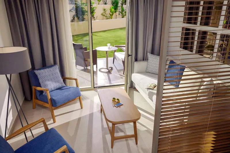 Un espace de séjour lumineux avec un canapé et des fauteuils près d'une terrasse.