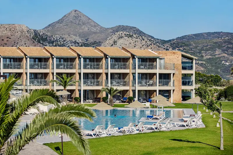 Bâtiment bas avec balcons donnant sur une piscine et un jardin verdoyant.