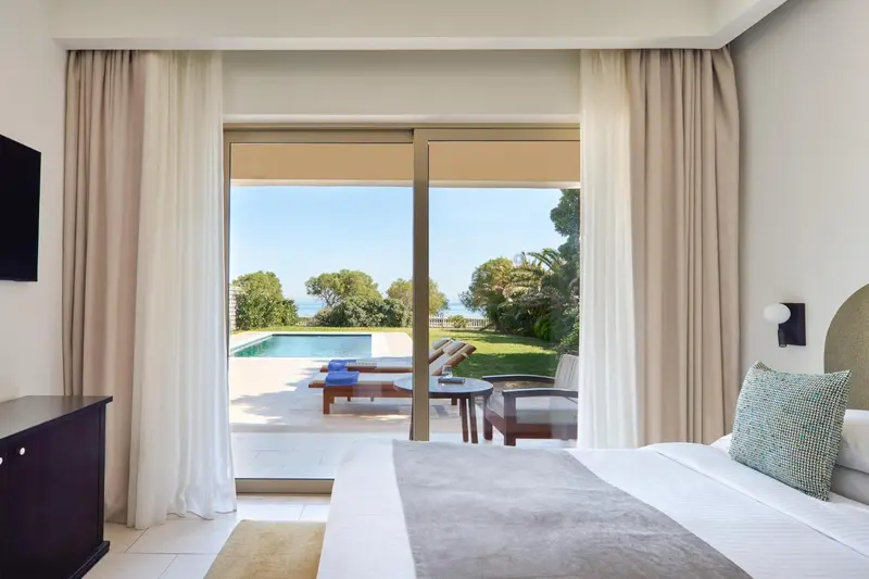 Une chambre lumineuse s'ouvre sur une terrasse et une piscine.