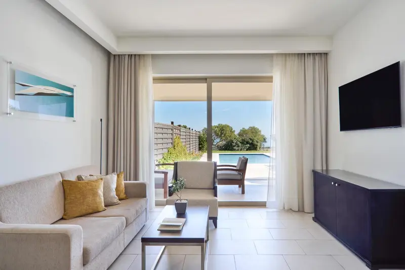 Un salon lumineux s'ouvre sur une terrasse avec vue sur une piscine.