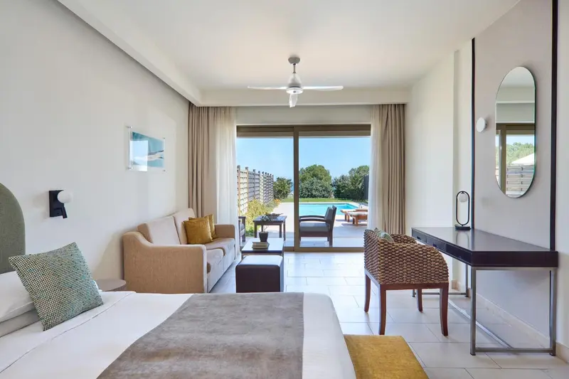 Une chambre lumineuse avec canapé et vue sur une piscine.