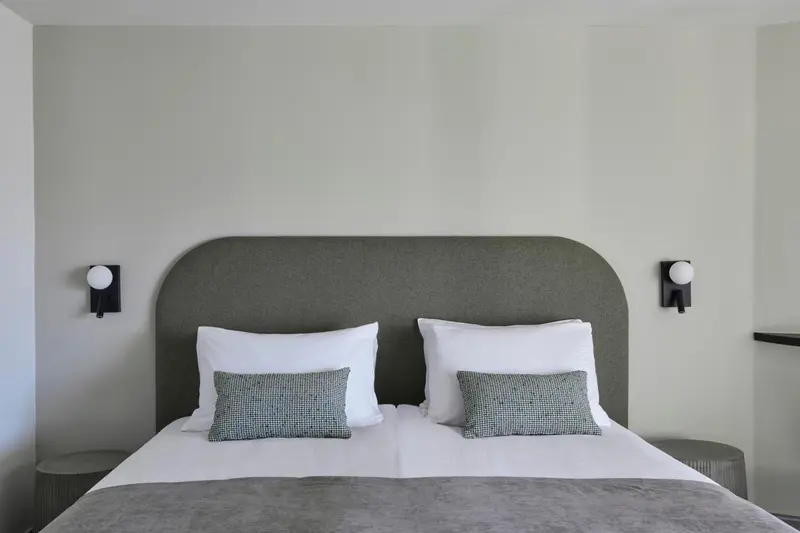 Un lit double avec des oreillers blancs et des coussins décoratifs dans une chambre.