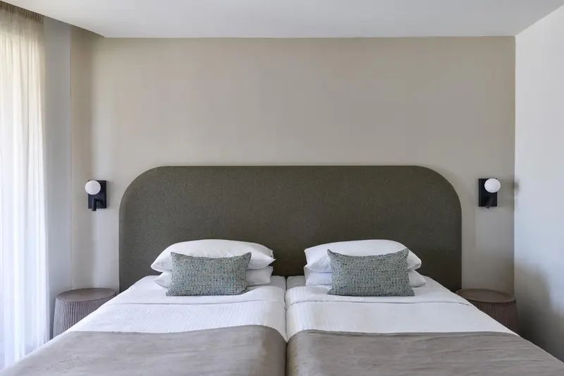 Une chambre avec deux lits simples et une tête de lit rembourrée.