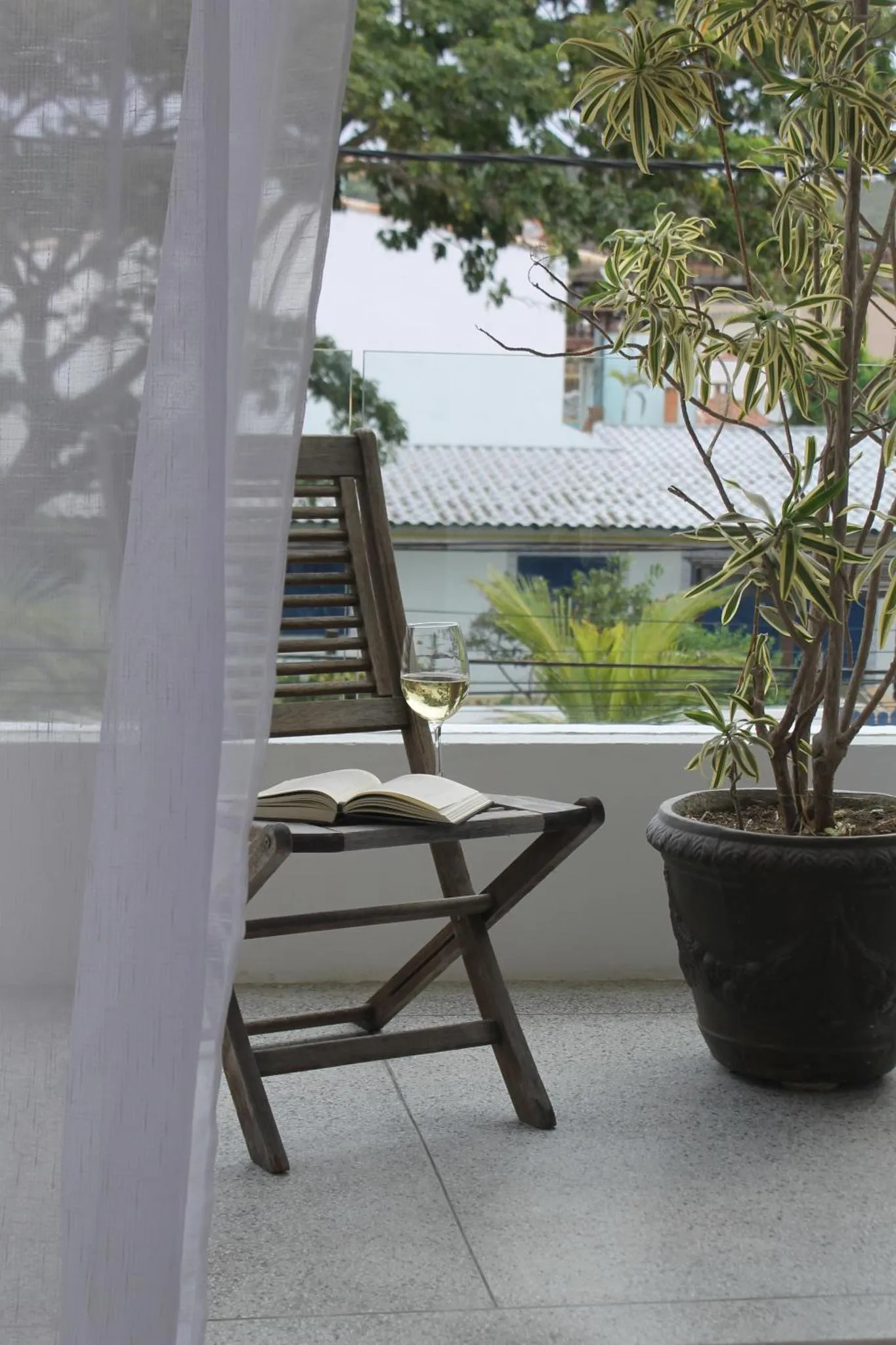 Une chaise longue avec un livre et un verre sur une terrasse ensoleillée.