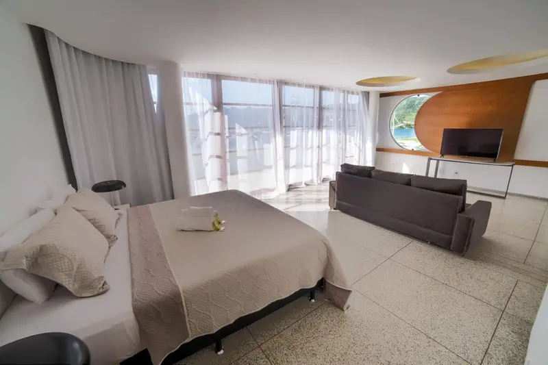 Une chambre lumineuse avec un grand lit et un coin salon.