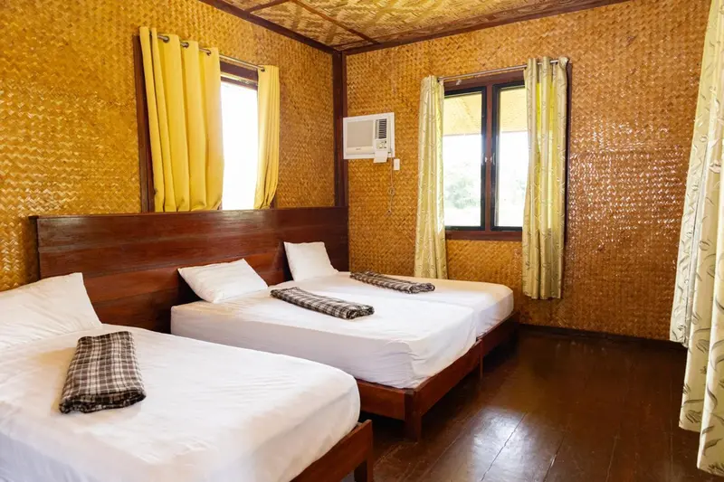 Chambre avec deux lits simples et décoration en fibres naturelles.