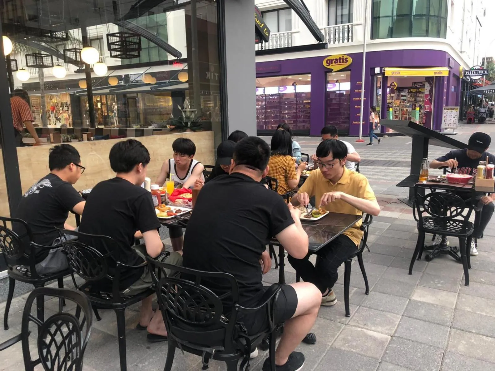 Des clients sont assis à des tables en extérieur pour déguster un repas.