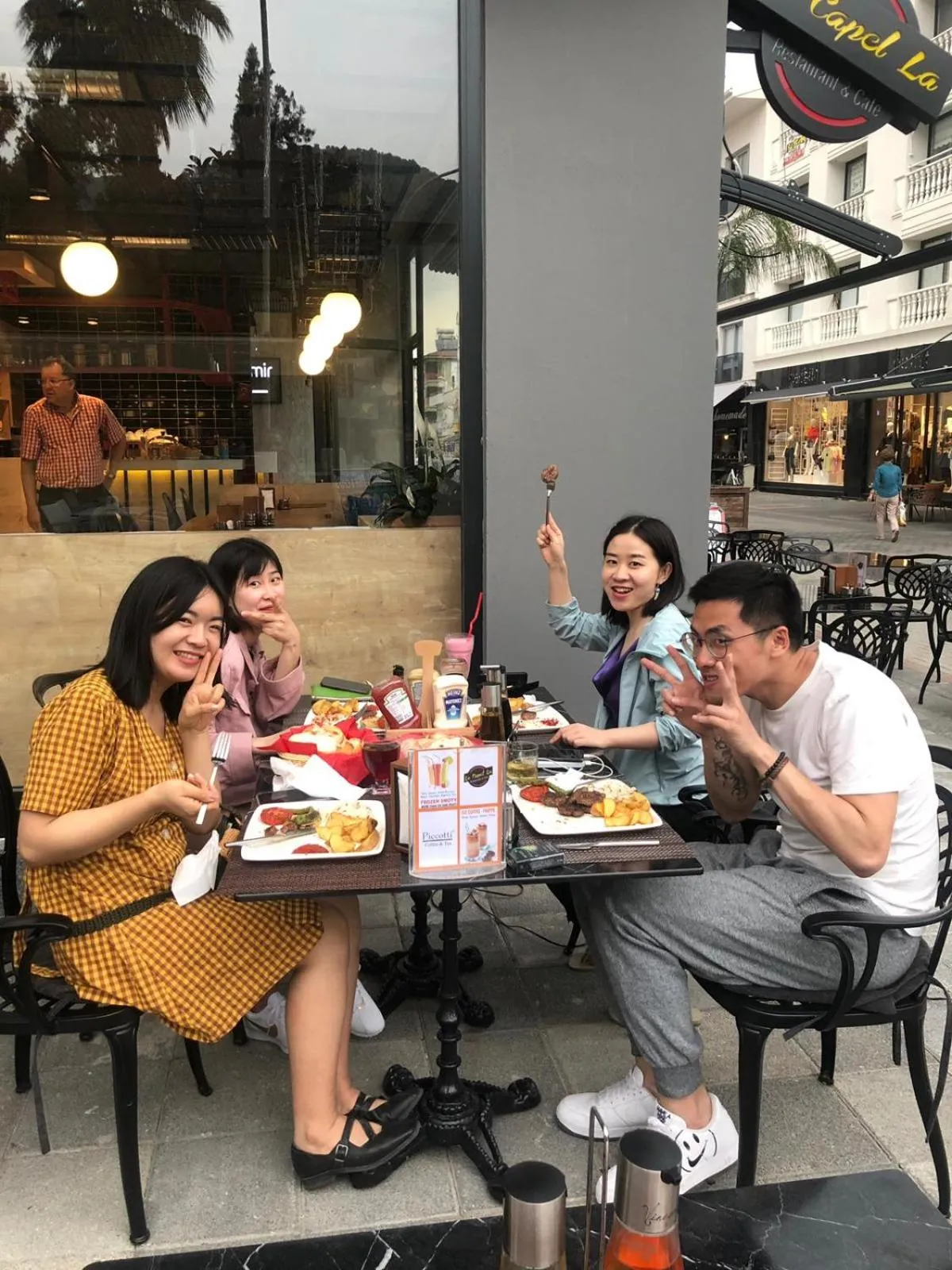 Des convives sont assis à une table en terrasse et dégustent un repas.