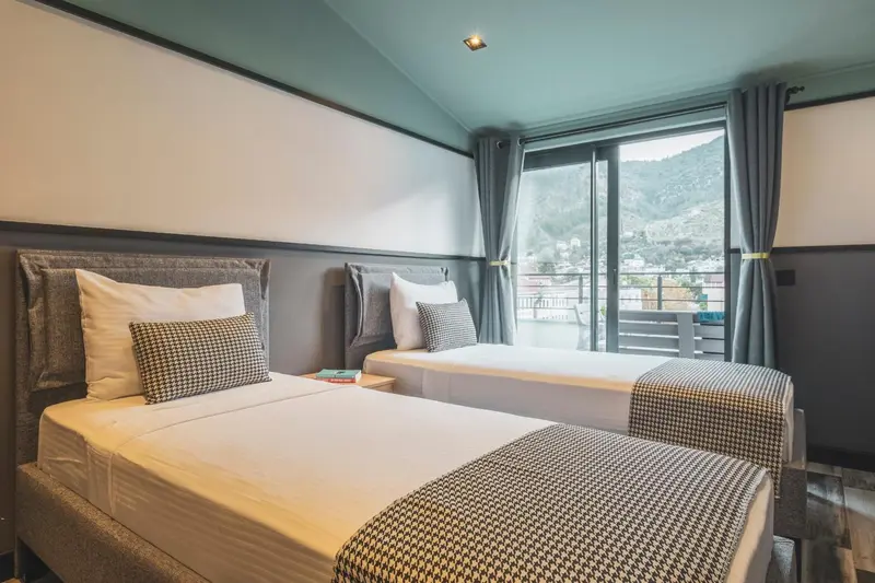 Une chambre avec deux lits simples et une vue sur un paysage montagneux.