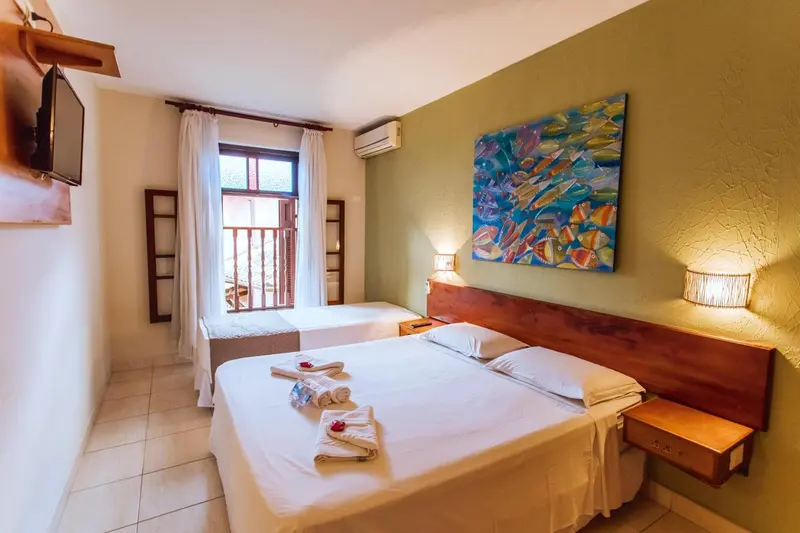 Une chambre lumineuse avec deux lits simples et une décoration murale colorée.
