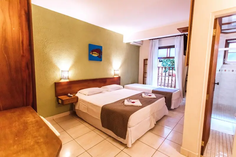 Chambre lumineuse avec un lit double et une vue sur une terrasse.