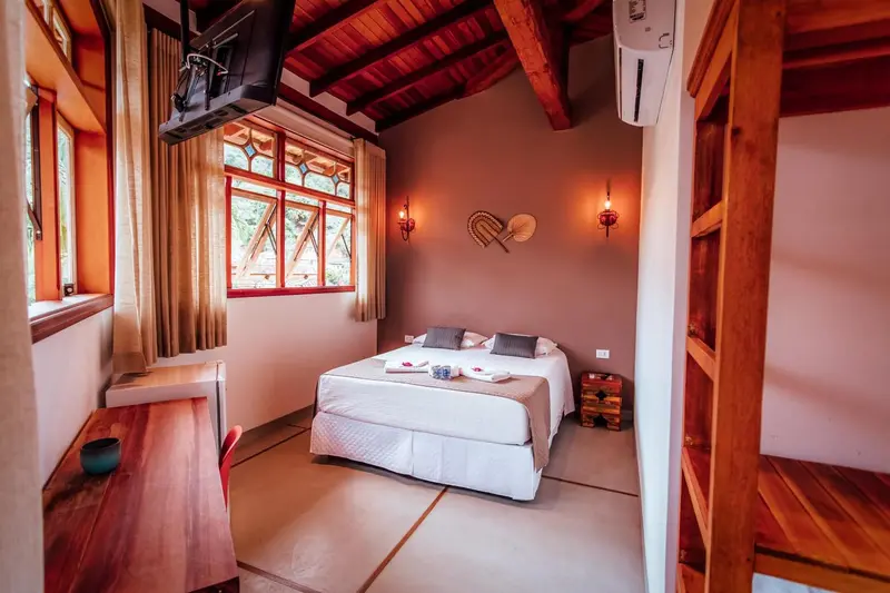 Une chambre lumineuse avec un lit double et un bureau en bois.