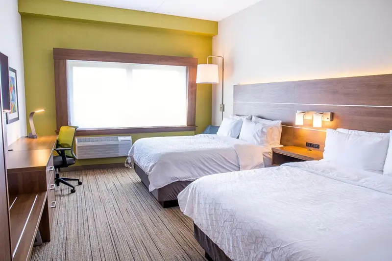 Une chambre d'hôtel lumineuse avec deux lits simples et un bureau.
