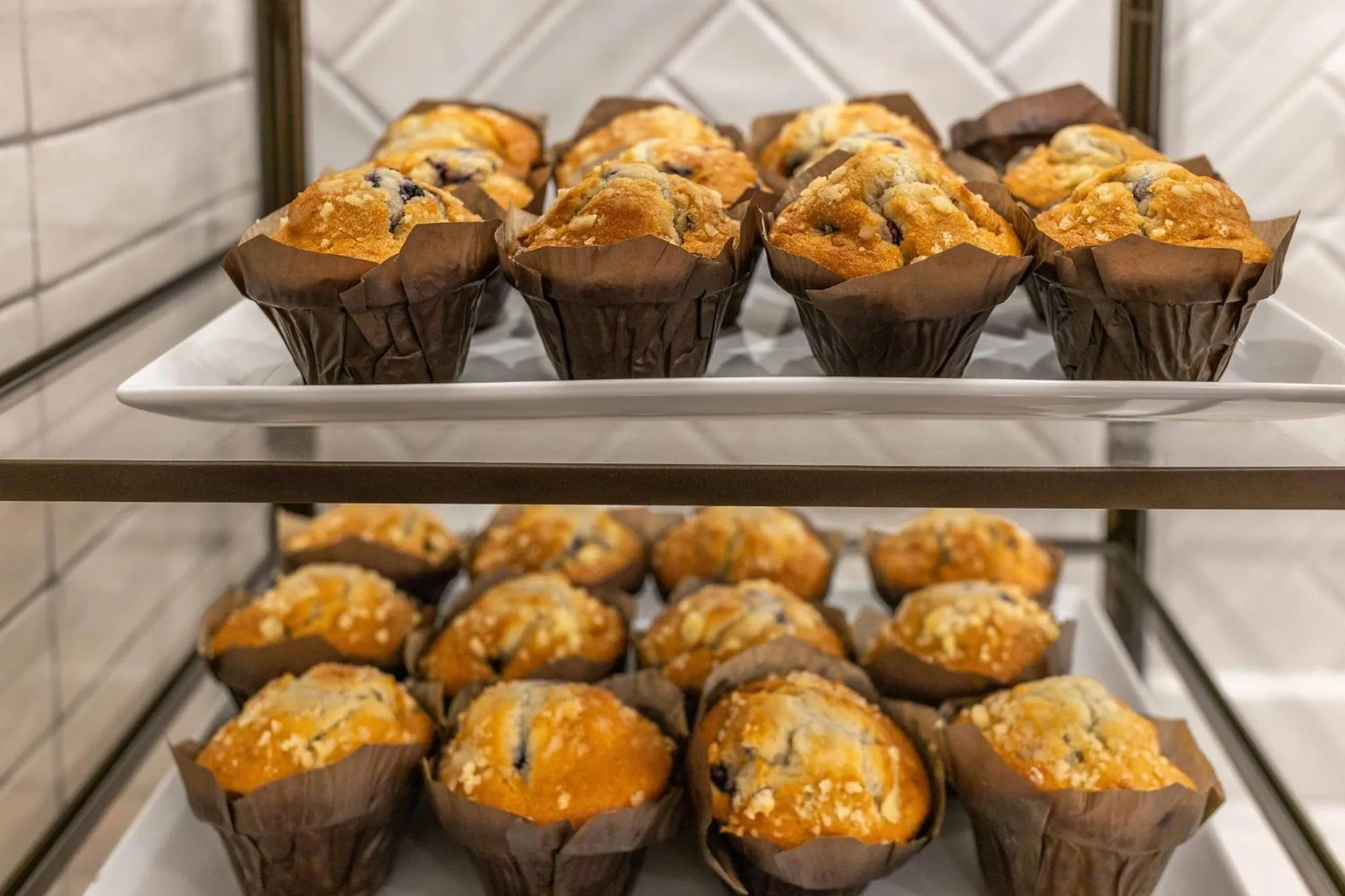 Des muffins aux myrtilles sont présentés sur un présentoir à pâtisseries.