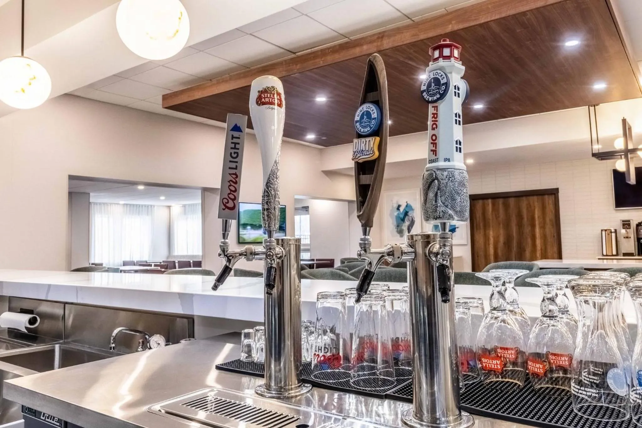 Un comptoir de bar en acier inoxydable présente des robinets à bière et des verres.