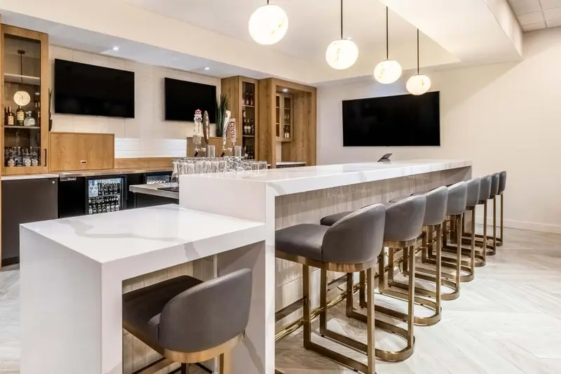 Un long comptoir de bar moderne avec des tabourets haut.