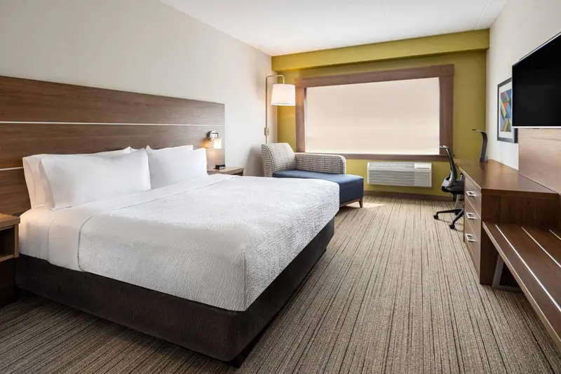 Une chambre d'hôtel lumineuse avec un grand lit et un fauteuil.
