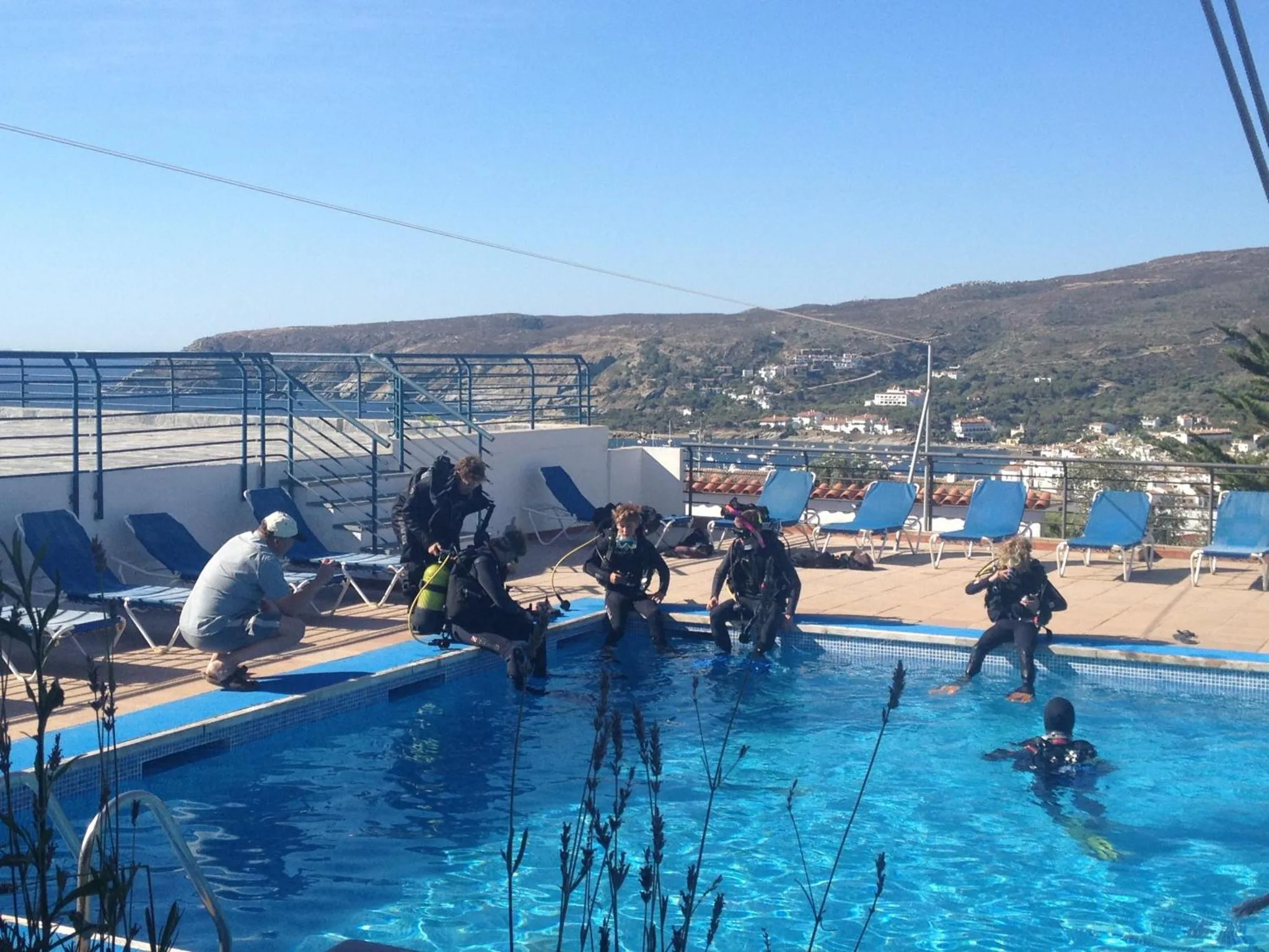 Personnes équipées près d'une piscine avec vue sur un paysage montagneux.