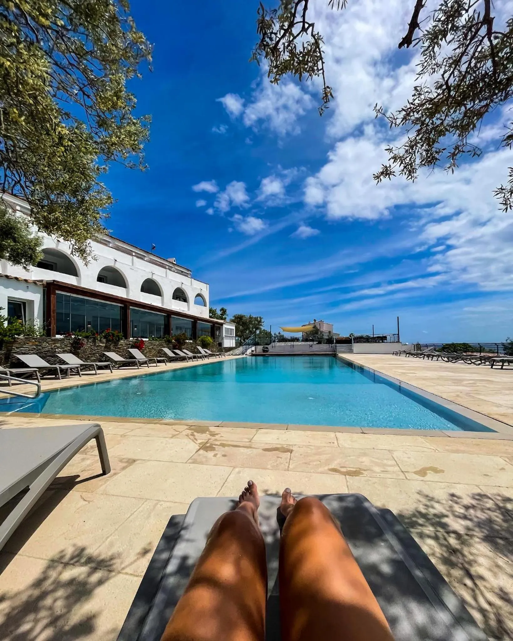 Transats au bord d'une piscine ensoleillée avec vue sur la mer.