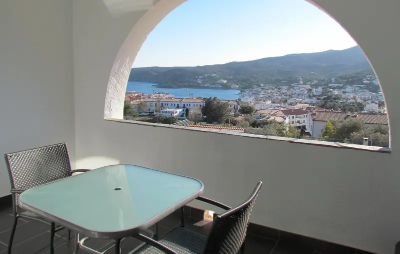 Vue sur une baie depuis une terrasse avec table et chaises.
