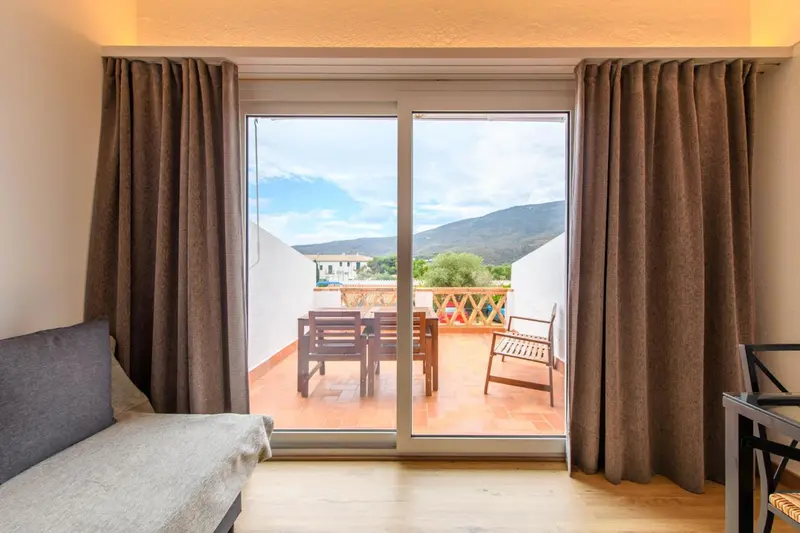 Une terrasse ensoleillée offre une vue sur les montagnes.