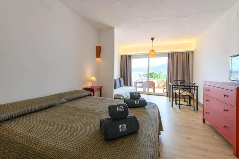 Une chambre lumineuse avec un lit double et un accès à une terrasse.