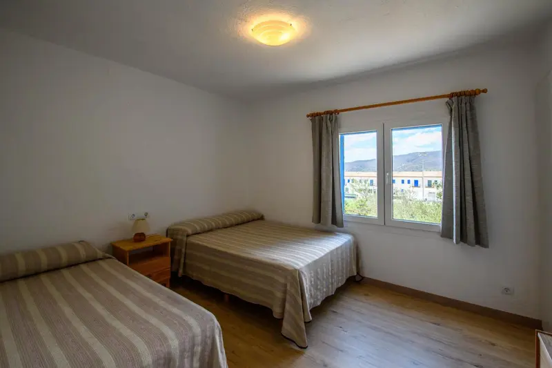Une chambre lumineuse avec deux lits simples et une vue sur le paysage.