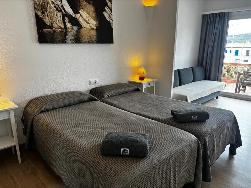 Une chambre lumineuse avec un lit double et un canapé près d'une fenêtre.