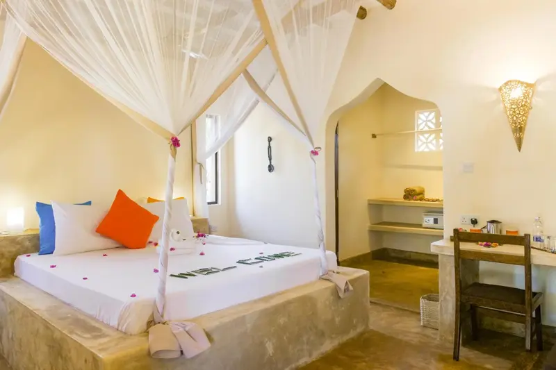Une chambre lumineuse avec un lit à baldaquin décoré de pétales de fleurs.