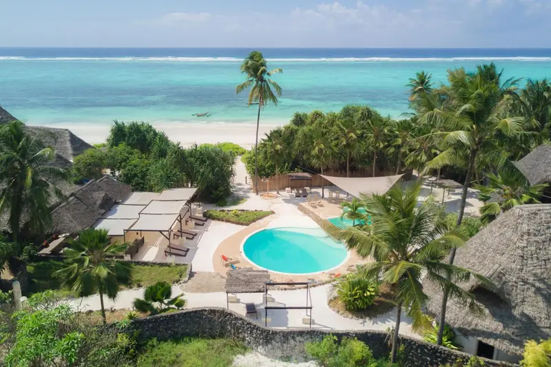 Vue aérienne d'un complexe hôtelier avec piscine et accès à la plage.