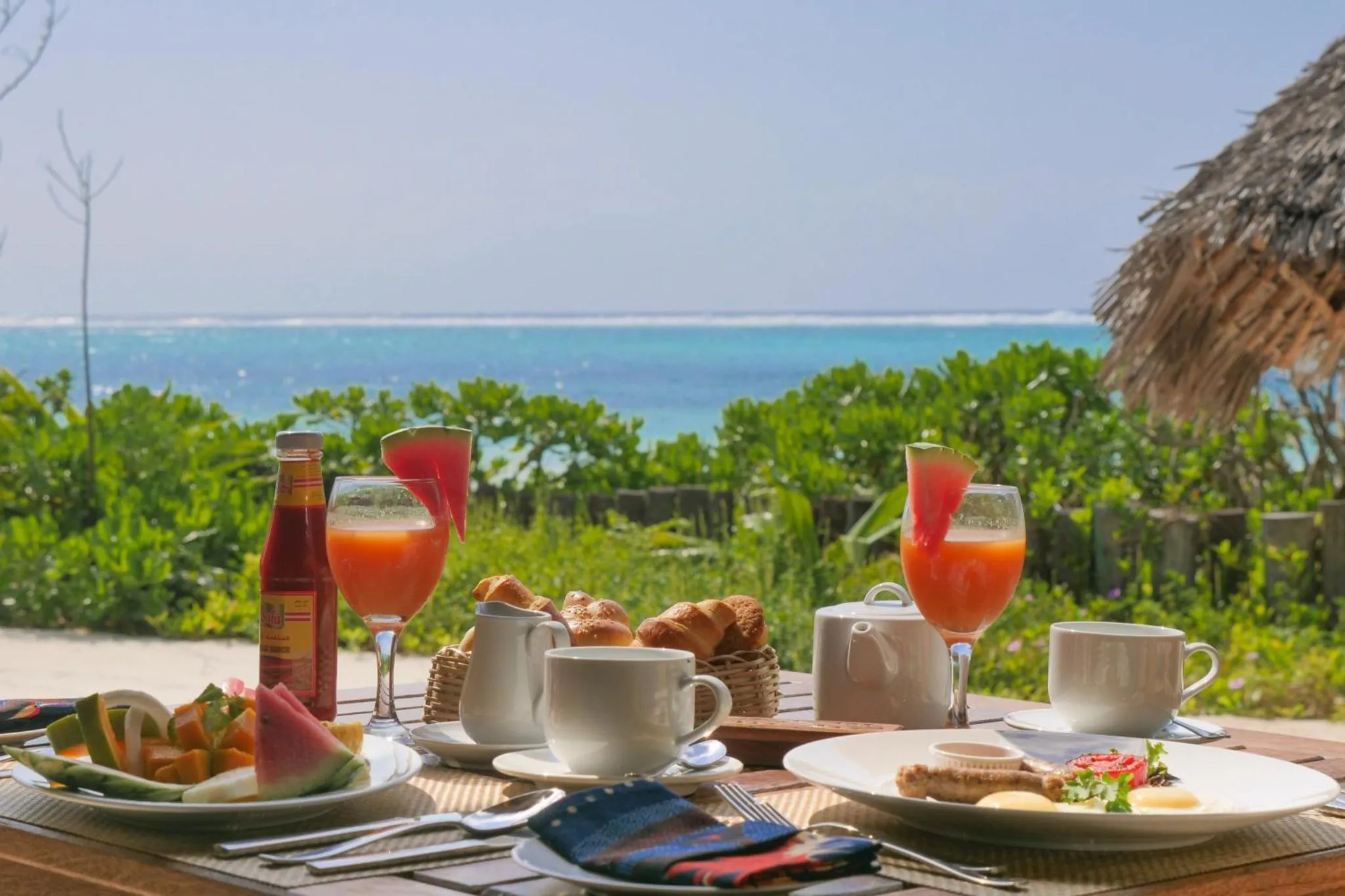 Une table est dressée avec des plats et des boissons face à la mer.