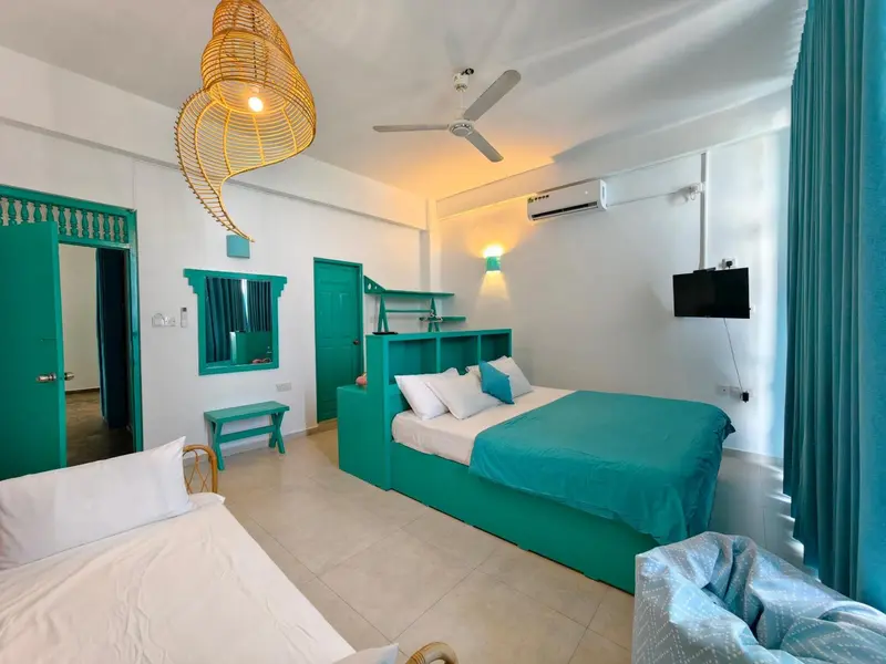 Une chambre lumineuse avec deux lits et une décoration turquoise.