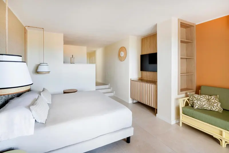 Une chambre lumineuse avec un grand lit et un coin salon.