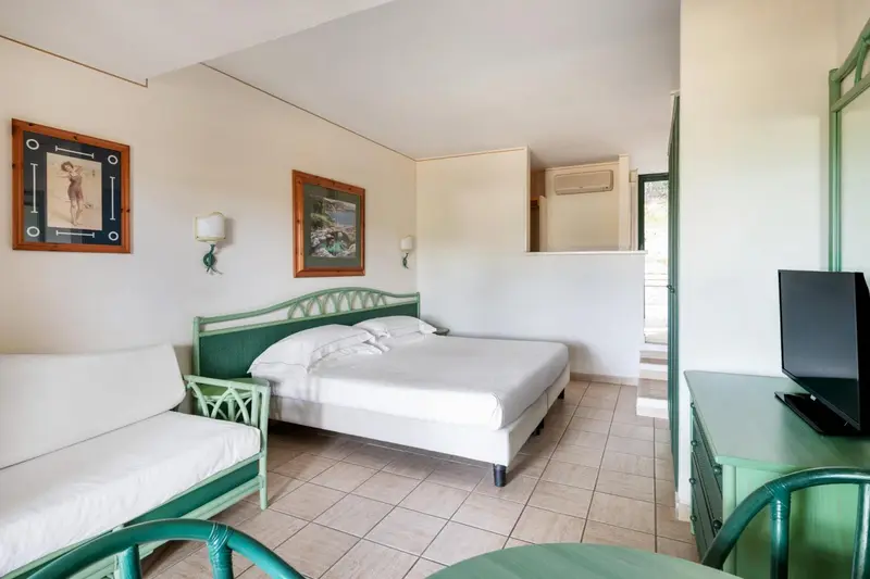 Une chambre lumineuse avec un lit double et un coin salon.