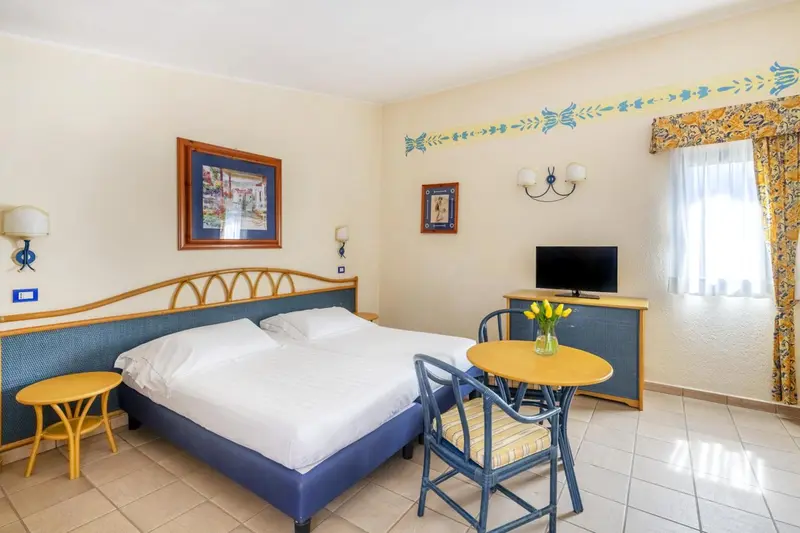 Une chambre lumineuse avec un lit double et une petite table.